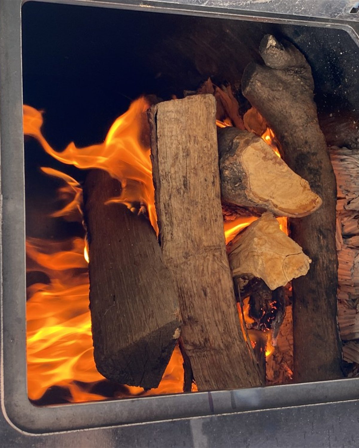 Leña ardiendo y brasas dentro de la cámara de combustión del Backyarder, en primer plano