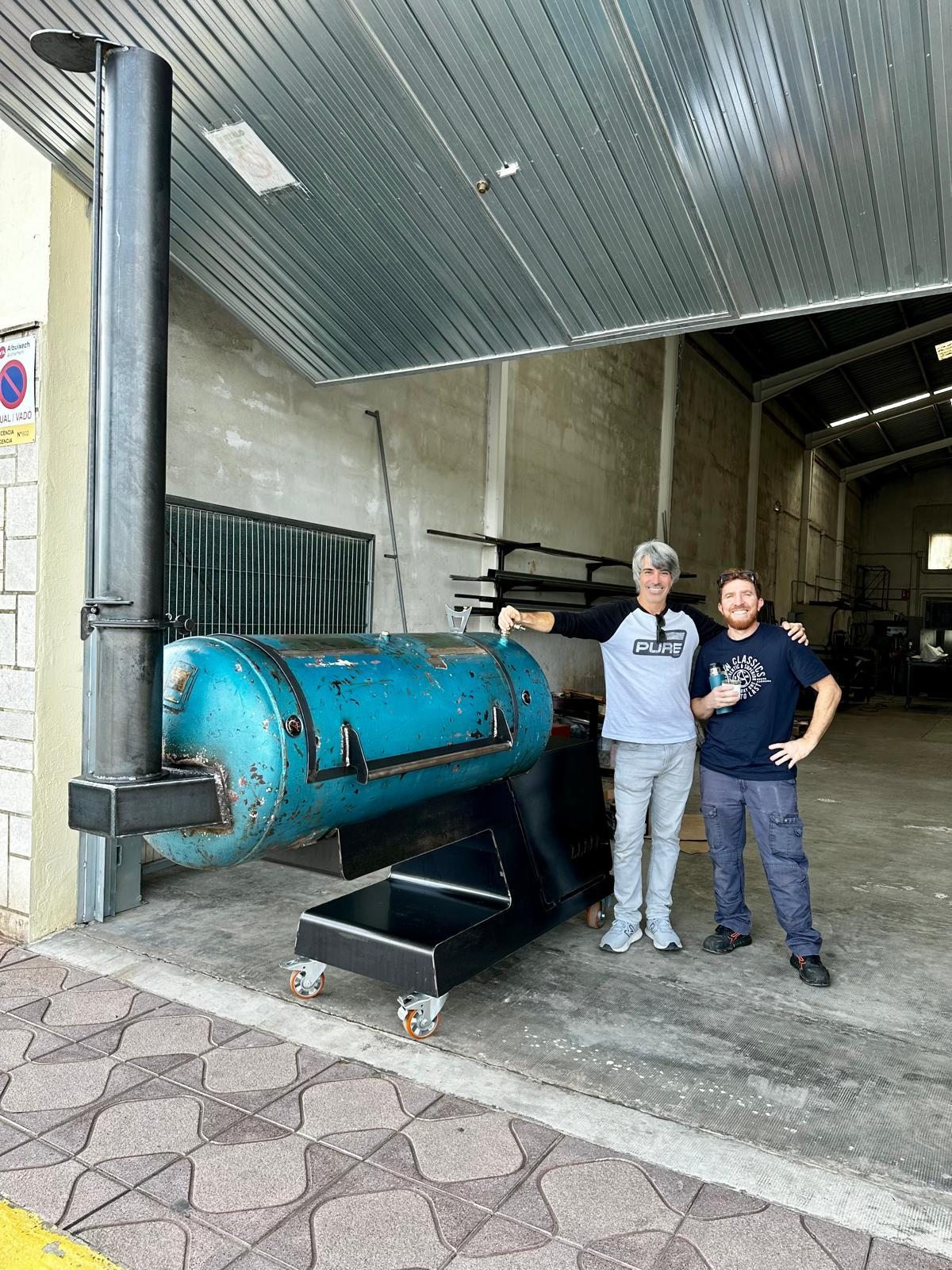 Marcos y Luciano en el taller de Albuixech, junto a The Beast, el primer ahumador que construyeron sobre un antiguo compresor de 250 litros
