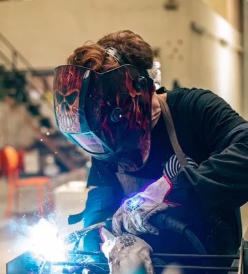 Soldador del taller de Puco Fuego con careta trabajando una unión del Backyarder, con las chispas de la soldadura en primer plano
